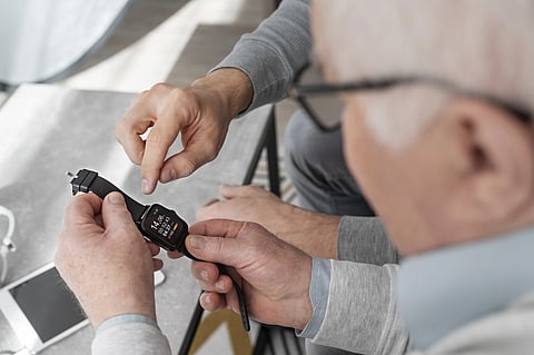 An elderly man is trying a digital watch. 