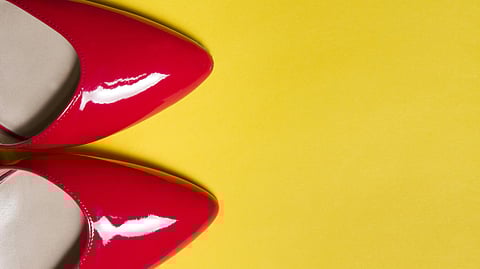Bright red patent leather shoes on a vibrant yellow background. 