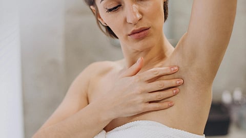 Woman in a white towel, raising one arm.