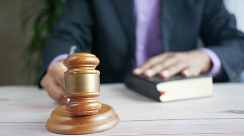 Judge at a desk, gavel in view, holding a book.