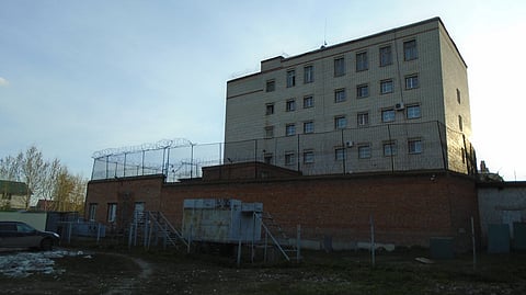 A tall, fenced brick building with barbed wire.