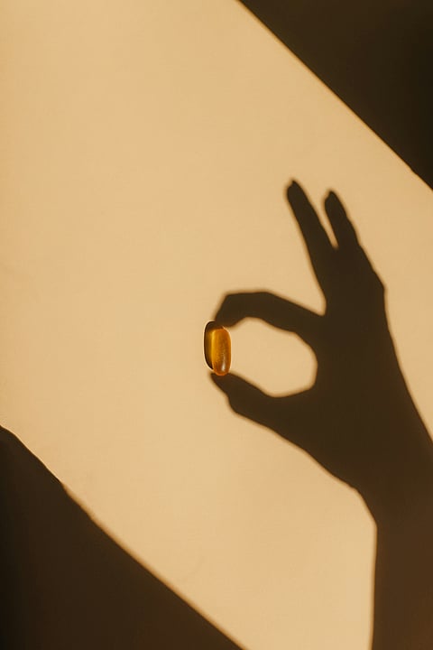 A person holds a yellow object in front of a dark shadow, creating a striking contrast in the image.