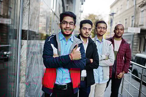 Group of four indian teen male students classmates spend time together outdoors.