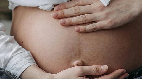 2 hands of a woman on her pregnant belly.