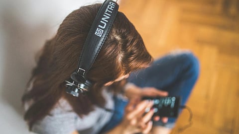 A girl looking down on phone with headphones on.
