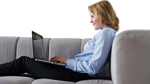 A woman sitting on a couch, using a laptop.