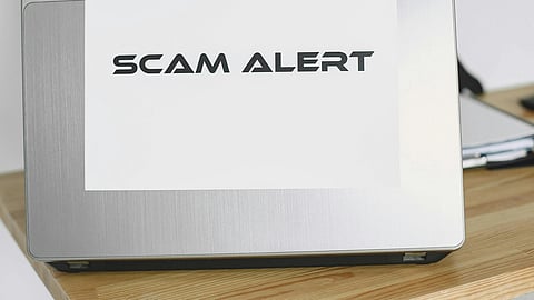 A laptop with a scam alert poster on the back.