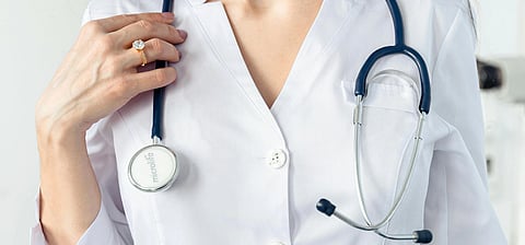 A doctor holding a stethoscope around neck.