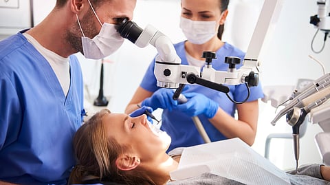 A woman receiving a dental examination from a dentist in a clinical setting.