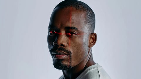 A man with striking red eyes wearing a white shirt, looking directly at the camera.