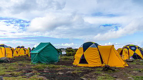 A campsite with yellow and green tents on rocky ground.
