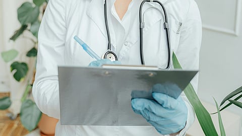 A doctor with a writing pad and stethoscope around neck.