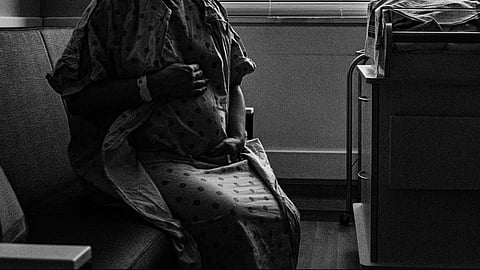 Pregnant woman holding belly in hospital.