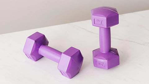 Two purple dumbbells are on a white marble surface.