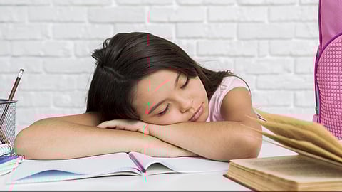 Schoolgirl asleep with head on copybook