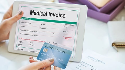 A person holding a tablet displaying a medical invoice and a credit card.