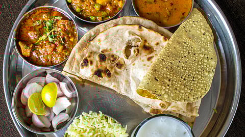 A food plate with chapati, papad, and vegitable curries.