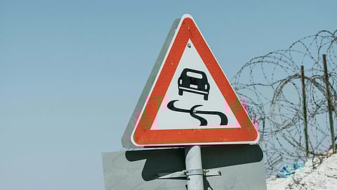Slippery road ahead warning sign.