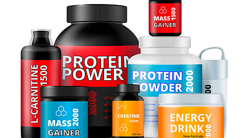 Colorful supplement containers labeled Protein Power, Mass Gainer, Energy Drink, L-Carnitine, and Creatine Drive are neatly arranged.