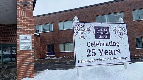 Sign celebrating Valley Medical Group's 25th anniversary stands in snowy foreground. Red brick building in background.