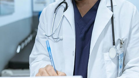 A doctor in white coat with stethoscope around neck.