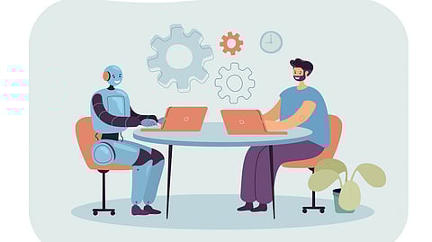 A robot and a person sit at a table, each with a laptop, symbolizing collaboration. 