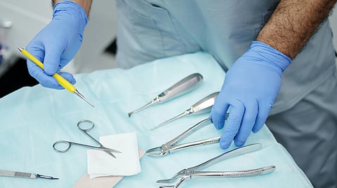 Surgical tools kept on table with blue sheet beneath.