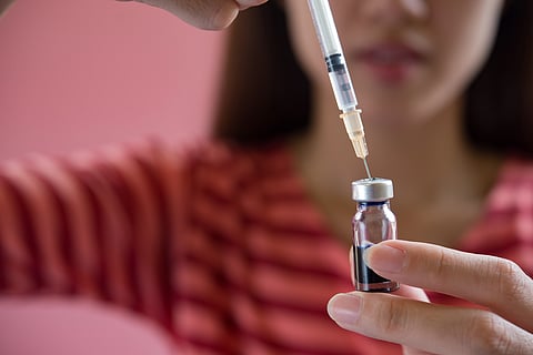 A young girl is taking some medication from an ampoule in a syringe. 