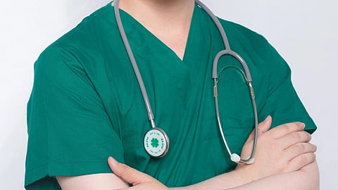 A doctor in green scrubs and stethoscope around neck.
