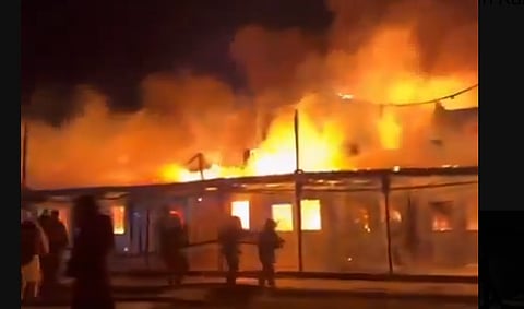 A building going up in flames and fire fighters trying to bring the fire under control. 