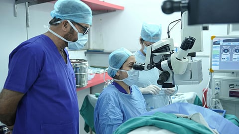 3 doctors during eye surgery with equipment.