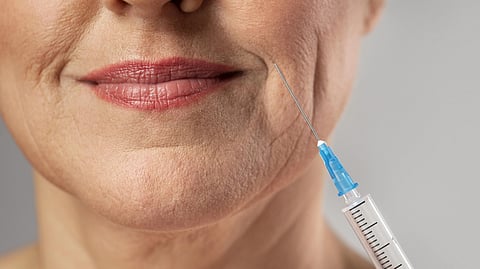 Smiley elder woman using injection for her mouth wrinkles