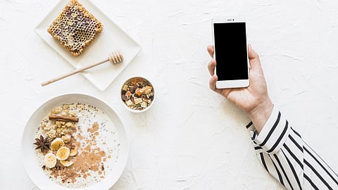 Oatmeals; dryfruits and honeycomb on table with cellphone in hands