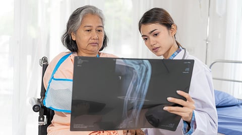 A doctor shows an elderly woman a clear X-ray in a bright hospital room.