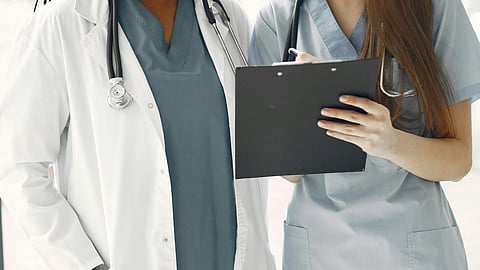 one medical student and one nursing student standing next to each other holding a writing pad.