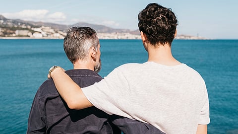 A father and son duo in front of sea.