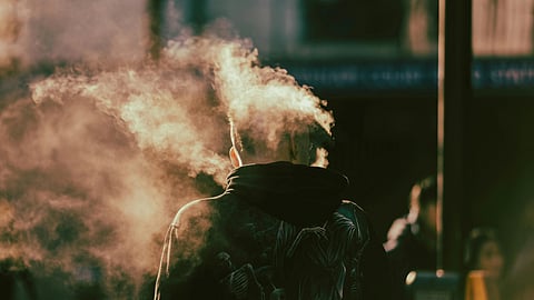 A man smokes under dim light.