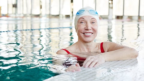 Smiling woman in a red swimsuit at an indoor pool.
