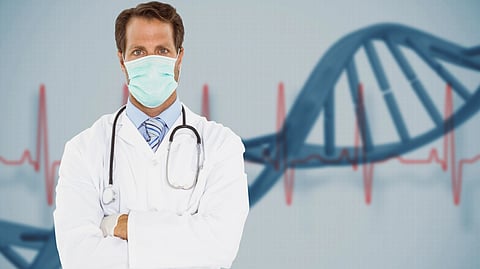 A doctor in a white coat and mask crosses his arms confidently. In the background, a large DNA strand and an EKG line are visible.