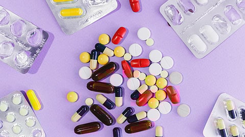 Various colorful pills and tablets scattered on a purple background.