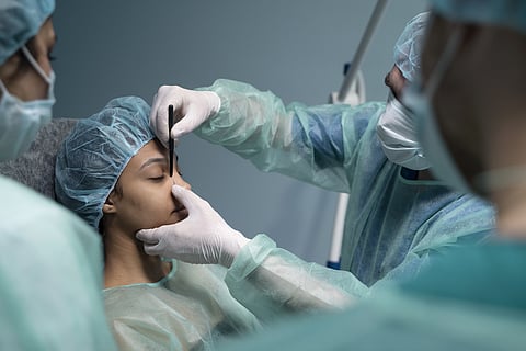 Side view of a patient being examined by surgeons before a facial plastic surgery. 