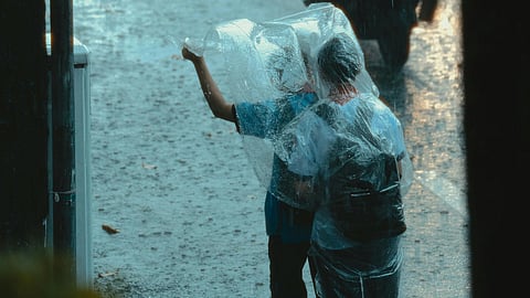 2 kids in rain with plastic sheets.