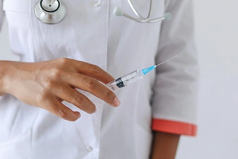 A doctor holds a syringe in a clinic, ready for treatment.