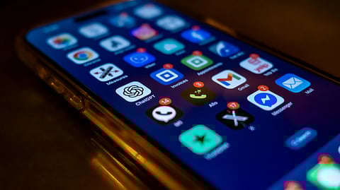 Close-up of a smartphone screen with various app icons, some showing red notification badges.