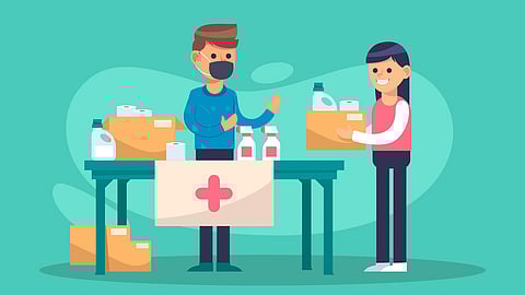 Two people exchanging donation boxes at a relief table with a medical cross banner.