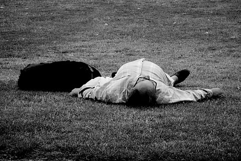 man lying on grass field in grayscale photography