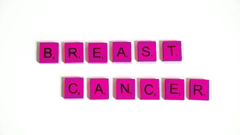 Pink Scrabble tiles spell "Breast Cancer" against a white background.