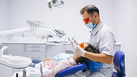 A woman patient is going through a routine dental checkup by a dentist.