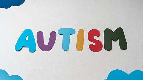 Colorful letters spell “AUTISM” on a white background, surrounded by blue cloud shapes.