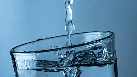A close-up of water pouring into a tilted glass.